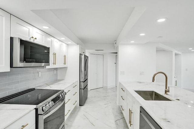 kitchen featuring backsplash, light stone counters, stainless steel appliances, sink, and white cabinets