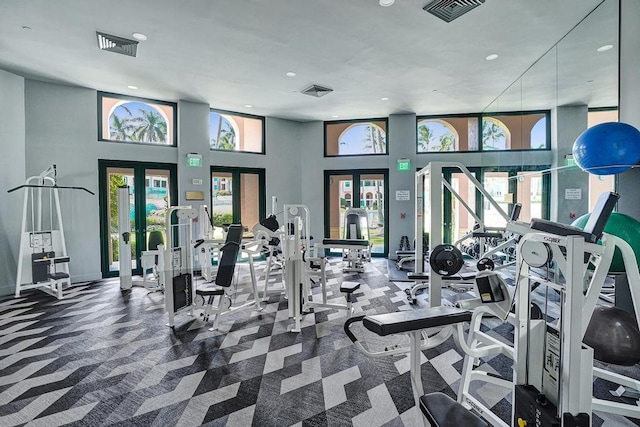 gym featuring french doors, carpet floors, and a high ceiling