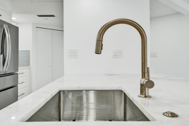 room details with stainless steel refrigerator, sink, and white cabinets