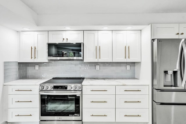 kitchen with light stone countertops, decorative backsplash, stainless steel appliances, and white cabinetry