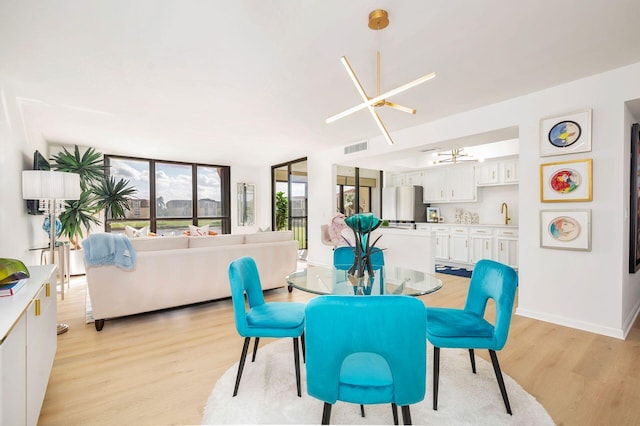 dining area with light hardwood / wood-style floors and an inviting chandelier