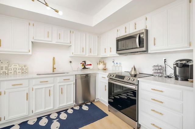 kitchen featuring white cabinetry, sink, stainless steel appliances, and light hardwood / wood-style floors