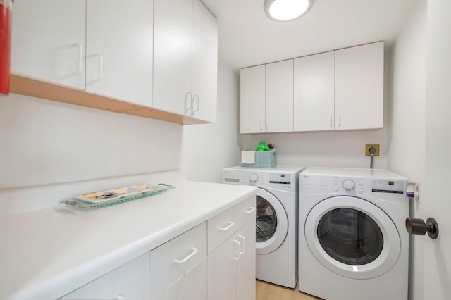 laundry room with cabinets, independent washer and dryer, and light hardwood / wood-style flooring