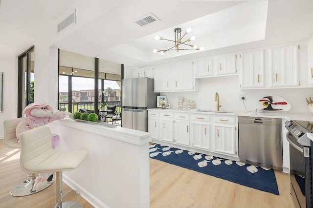 kitchen with white cabinets, stainless steel appliances, and light hardwood / wood-style flooring