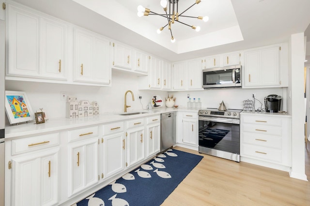 kitchen with a raised ceiling, sink, white cabinets, and stainless steel appliances