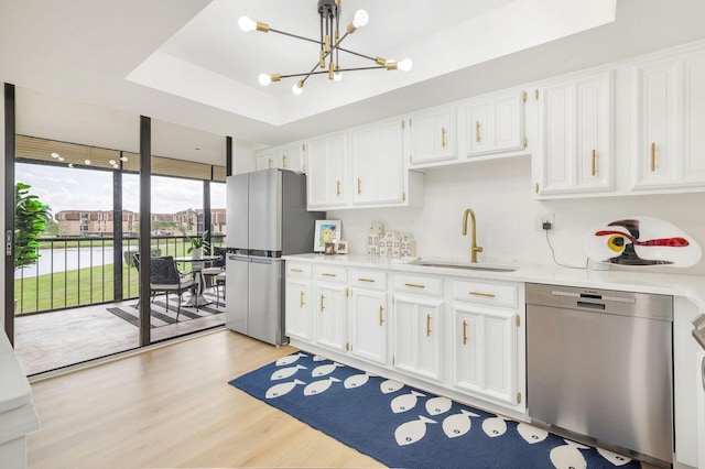 kitchen featuring a raised ceiling, sink, decorative light fixtures, white cabinetry, and stainless steel appliances