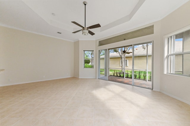 tiled empty room featuring ceiling fan, a raised ceiling, and ornamental molding