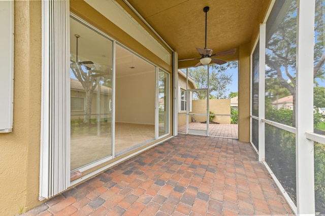 unfurnished sunroom with ceiling fan