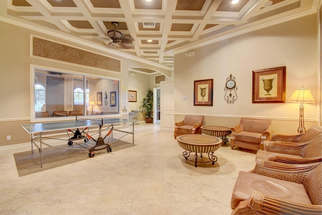 playroom with ceiling fan, coffered ceiling, a high ceiling, and ornamental molding