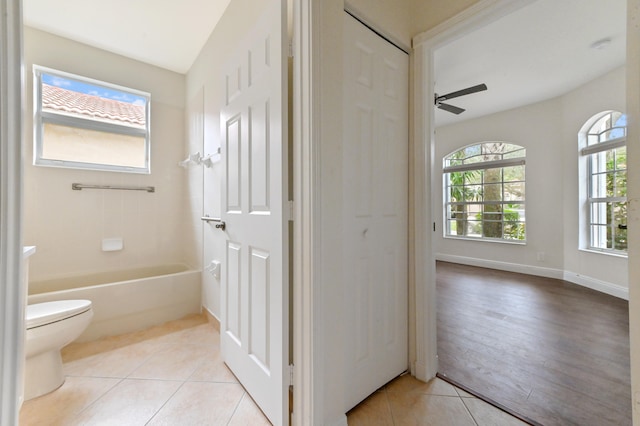 bathroom with shower / bathtub combination, ceiling fan, hardwood / wood-style floors, toilet, and lofted ceiling