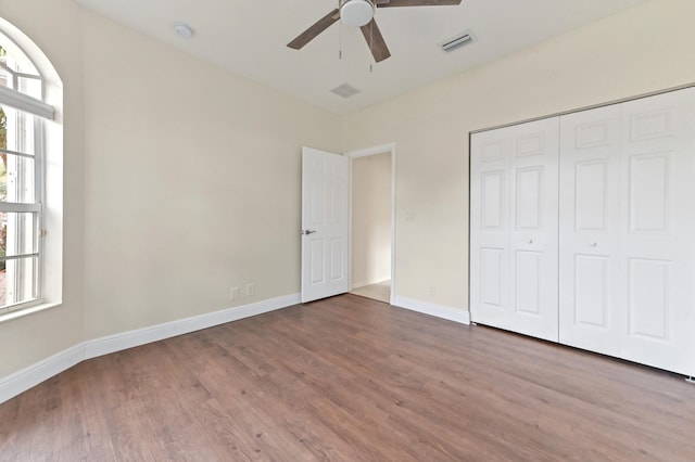 unfurnished bedroom featuring ceiling fan, a closet, and wood-type flooring