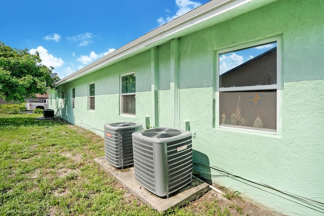 view of side of home with central AC unit and a yard