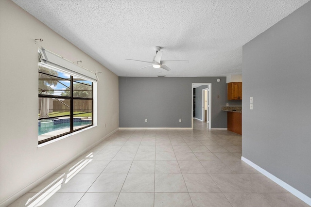 empty room featuring ceiling fan, light tile patterned flooring, and a textured ceiling