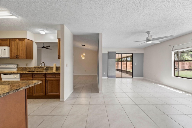 kitchen with a textured ceiling, plenty of natural light, white appliances, and hanging light fixtures