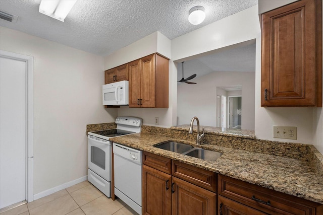 kitchen featuring lofted ceiling, white appliances, stone counters, sink, and light tile patterned floors