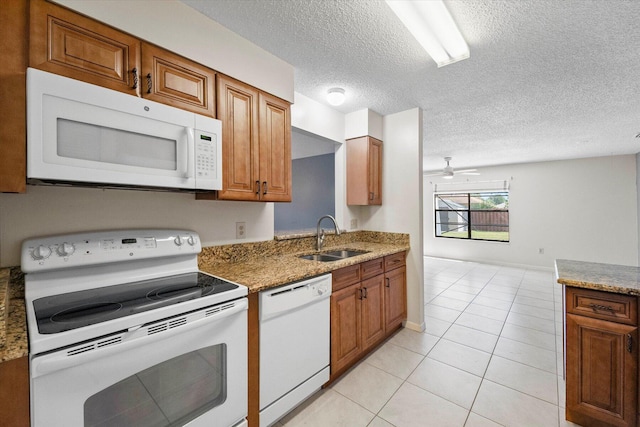 kitchen with sink, light stone counters, a textured ceiling, white appliances, and light tile patterned flooring