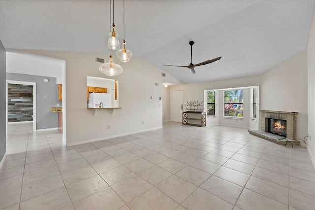 unfurnished living room with ceiling fan, light tile patterned flooring, a textured ceiling, and a brick fireplace