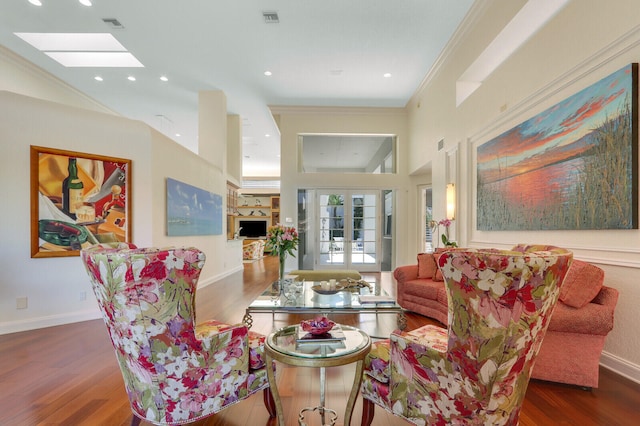 living room with hardwood / wood-style floors, french doors, ornamental molding, and vaulted ceiling with skylight