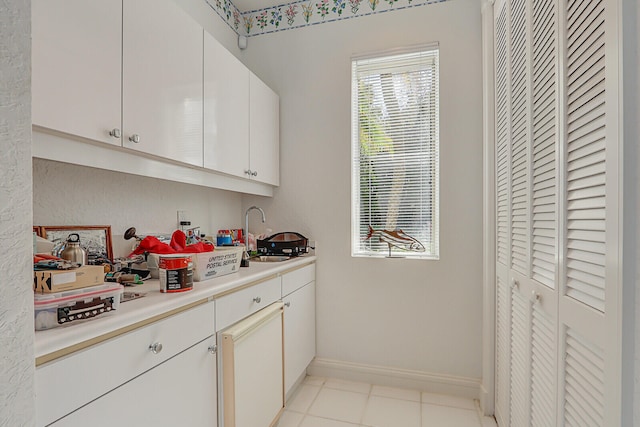 kitchen with white cabinets, light tile patterned floors, and sink