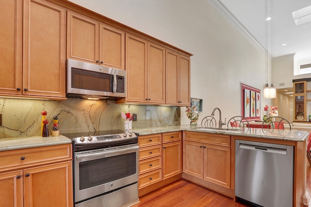 kitchen featuring hanging light fixtures, stainless steel appliances, kitchen peninsula, crown molding, and light wood-type flooring