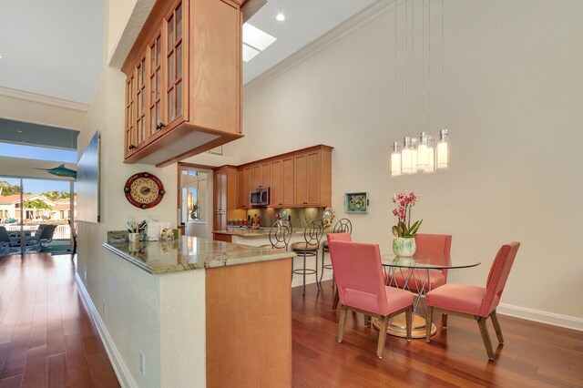 kitchen with light stone countertops, high vaulted ceiling, dark hardwood / wood-style floors, kitchen peninsula, and crown molding