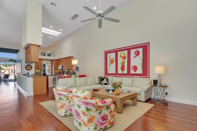 living room with dark hardwood / wood-style floors, ceiling fan, ornamental molding, and a high ceiling