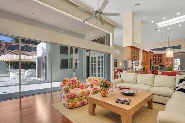 living room with a towering ceiling, light wood-type flooring, and ceiling fan