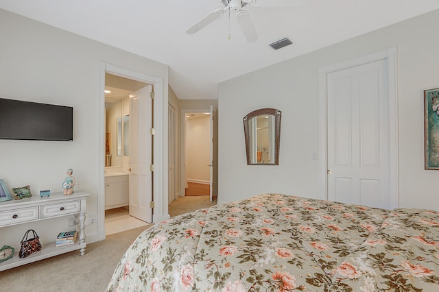 bedroom featuring connected bathroom, ceiling fan, a closet, and light colored carpet