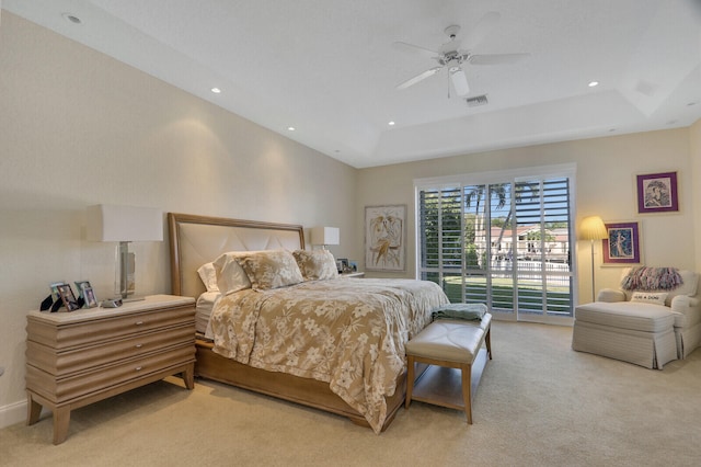 carpeted bedroom featuring ceiling fan, access to exterior, and a tray ceiling