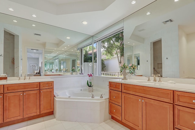 bathroom with tiled tub, tile patterned flooring, and vanity