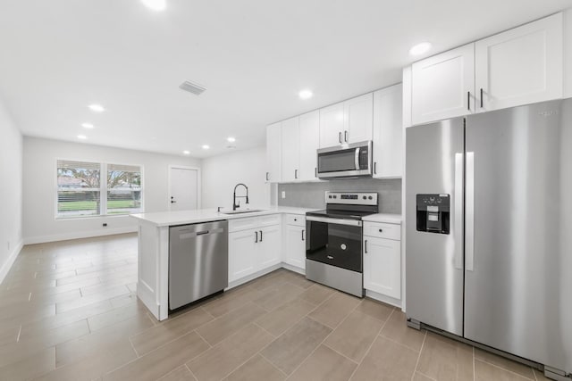 kitchen with kitchen peninsula, sink, white cabinets, and appliances with stainless steel finishes