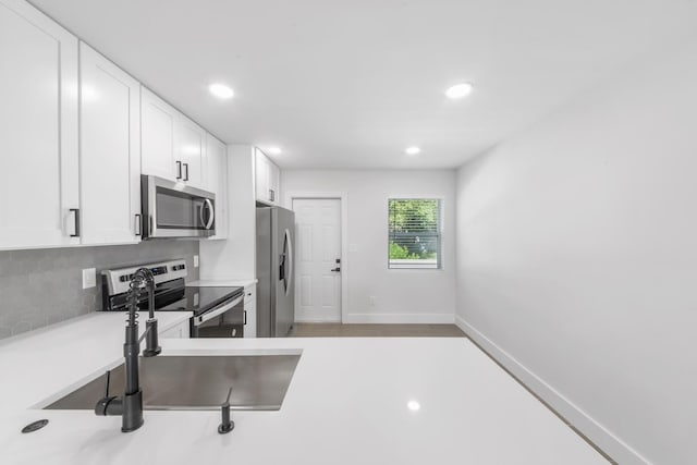 kitchen featuring decorative backsplash, white cabinetry, sink, and stainless steel appliances