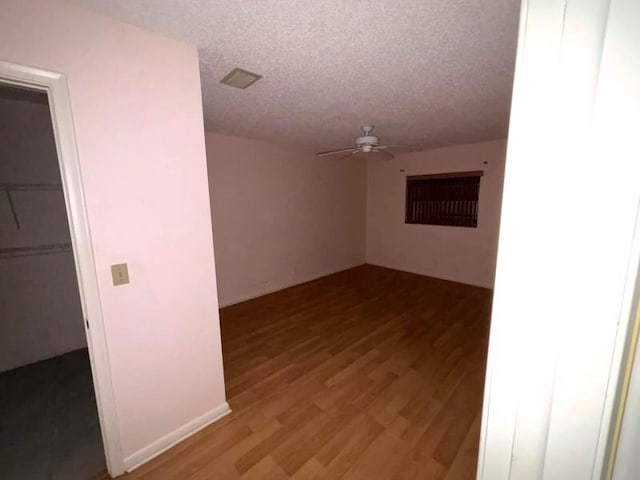 unfurnished room with ceiling fan, wood-type flooring, and a textured ceiling