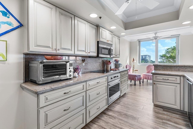 kitchen featuring crown molding, ceiling fan, appliances with stainless steel finishes, a tray ceiling, and white cabinets