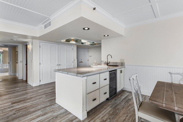 kitchen featuring sink, white cabinetry, dark hardwood / wood-style floors, kitchen peninsula, and beverage cooler