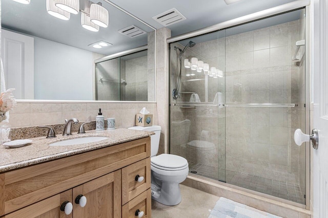 bathroom with vanity, tasteful backsplash, a shower with shower door, tile patterned floors, and toilet