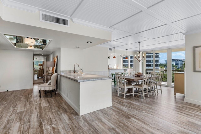 kitchen with decorative light fixtures, wood-type flooring, a notable chandelier, kitchen peninsula, and floor to ceiling windows