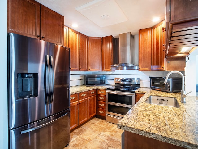 kitchen with wall chimney exhaust hood, light stone counters, sink, and appliances with stainless steel finishes