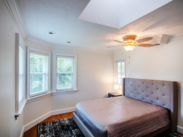 bedroom with hardwood / wood-style flooring, ceiling fan, ornamental molding, and a textured ceiling