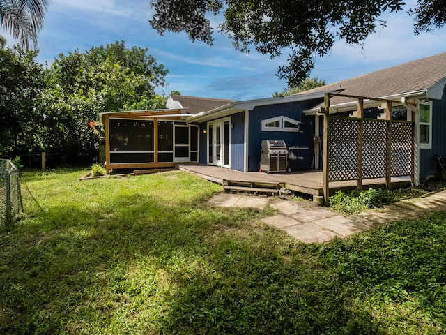 back of property with a yard, a wooden deck, and a sunroom