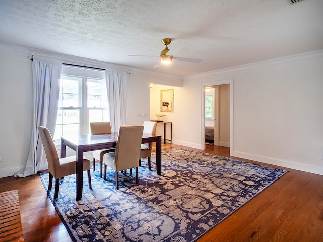 dining room with crown molding, ceiling fan, dark wood-type flooring, and a textured ceiling