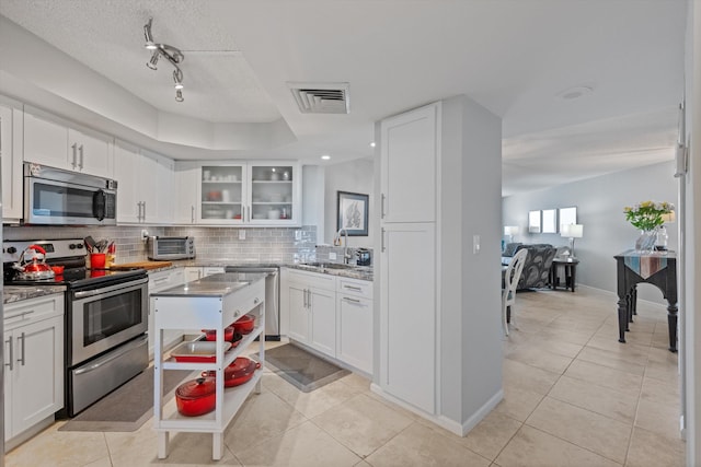 kitchen featuring decorative backsplash, appliances with stainless steel finishes, white cabinetry, and sink