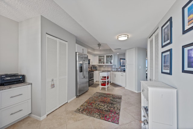 kitchen featuring white cabinetry, sink, stainless steel appliances, tasteful backsplash, and light tile patterned flooring