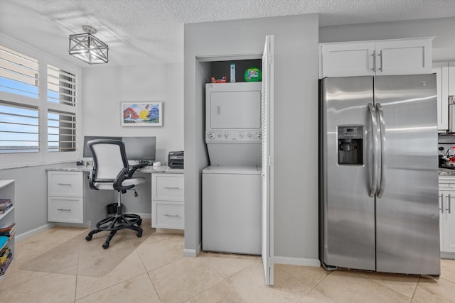 office space with a textured ceiling, light tile patterned flooring, and stacked washer / drying machine