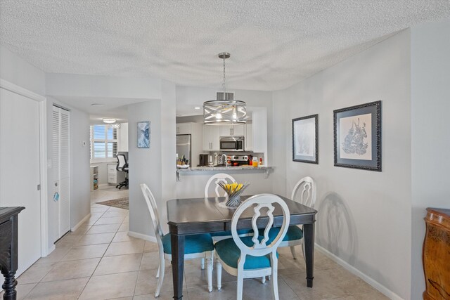 dining area with light tile patterned floors, a textured ceiling, and an inviting chandelier