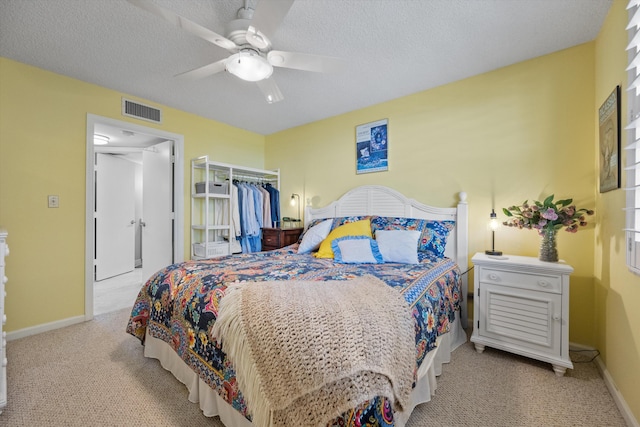 carpeted bedroom with a textured ceiling, a closet, and ceiling fan