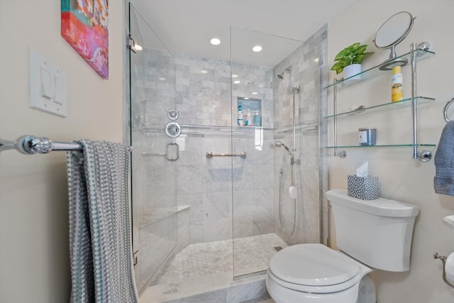 bathroom featuring a shower with door and toilet