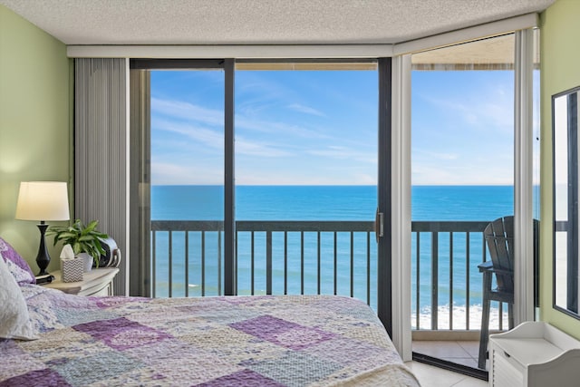 bedroom featuring tile patterned floors, a water view, a textured ceiling, and multiple windows