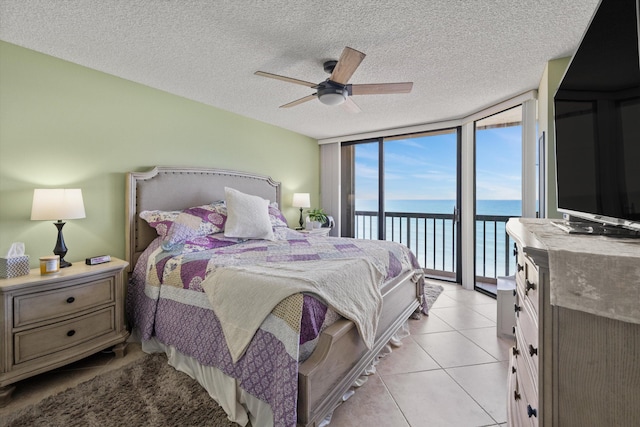 tiled bedroom with ceiling fan, expansive windows, and a textured ceiling