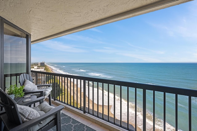 balcony featuring a water view and a beach view